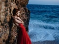 Woman in red dress rocky stone landscape ocean waves Royalty Free Stock Photo