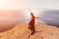 Woman red dress sea. Female dancer in a long red dress posing on a beach with rocks on sunny day. Girl on the nature on Royalty Free Stock Photo