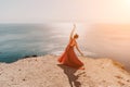 Woman red dress sea. Female dancer in a long red dress posing on a beach with rocks on sunny day. Girl on the nature on Royalty Free Stock Photo