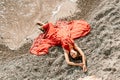 Woman red dress sea. Female dancer in a long red dress posing on a beach with rocks on sunny day Royalty Free Stock Photo
