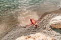 Woman red dress sea. Female dancer in a long red dress posing on a beach with rocks on sunny day Royalty Free Stock Photo