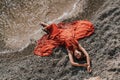 Woman red dress sea. Female dancer in a long red dress posing on a beach with rocks on sunny day Royalty Free Stock Photo
