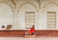 Woman in red dress sitting at the Red Fort in Agra