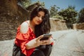 woman in red dress sitting looking at her phone in a park. Royalty Free Stock Photo