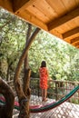 A woman in a red dress stands on the terrace of a wooden house and enjoys the view Royalty Free Stock Photo