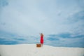 Woman in red dress with suitcase looking in binoculars Royalty Free Stock Photo