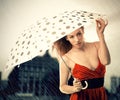Woman in red dress with umbrella under rain on night city background