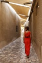A woman in a red dress walking on a narrow street in Bastakia area of old town Dubai Royalty Free Stock Photo