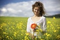 Woman with red flowers in rapeseed field.