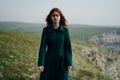 Woman with red hair on a cliff of a mountain near the sea, the wind Royalty Free Stock Photo