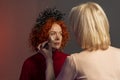 Woman with red hair doing makeup Beautician, applying powder to her face with a large brush, powdering the skin, selective focus.