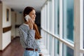 A woman with red hair with a phone in her hands talks and laughs while looking out the window at the city Royalty Free Stock Photo