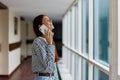 A woman with red hair with a phone in her hands talks and laughs while looking out the window at the city Royalty Free Stock Photo