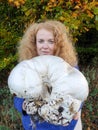 A woman with red hair proudly shows the big mushroom she has found, a giant bovist Royalty Free Stock Photo