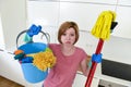 Woman with red hair in rubber washing gloves holding cleaning bucket mop and broom Royalty Free Stock Photo