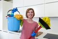 Woman with red hair in rubber washing gloves holding cleaning bucket mop and broom Royalty Free Stock Photo