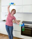 Woman with red hair in rubber washing gloves holding cleaning spray bottle and scourer