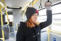 A woman with red hair stands while riding a bus Royalty Free Stock Photo