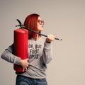 A woman with red hair in the Studio holding a fire extinguisher. An emotional bright woman extinguishes everything with