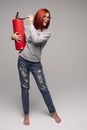 A woman with red hair in the Studio holding a fire extinguisher. An emotional bright woman extinguishes everything with