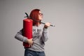 A woman with red hair in the Studio holding a fire extinguisher. An emotional bright woman extinguishes everything with