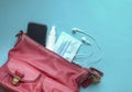 Woman red handbag with face mask, hand sanitizer, ear phones and smartphone Royalty Free Stock Photo