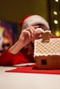 Woman in red hat building gingerbread house.