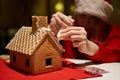 Woman in red hat building gingerbread house.