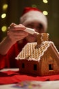 Woman in red hat building gingerbread house.