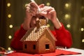 Woman in red hat building gingerbread house.