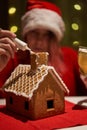 Woman in red hat building gingerbread house.