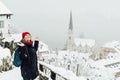 Woman in red hat enjoying the view over Hallstatt old town during snow storm, Austria