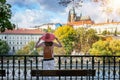 Woman with red hat enjoys the view to the castle of Prague, Czech Republic