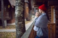 woman in a red hat and scarf and a mug stands at a wooden house in the woods Royalty Free Stock Photo