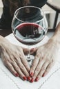 Woman in red holding wine glass. A young beautiful girl in black dress sits in a restaurant and drinks wine from a glass. close up Royalty Free Stock Photo