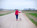 Woman with a red jacket go walkies with a pug on a gravel path Royalty Free Stock Photo