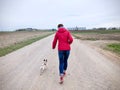 Woman with a red jacket go walkies with a pug on a gravel path Royalty Free Stock Photo