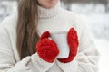 Woman in red knitted mittens holds cup of hot drink outdoors. Close-up of girls hands. Warm drinks in winter Royalty Free Stock Photo