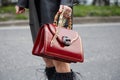 Woman with red leather bag with tiger head with gems and bamboo handle before Alberta Ferretti fashion show,