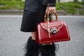 Woman with red leather bag with tiger head with gems and bamboo handle before Alberta Ferretti fashion show,