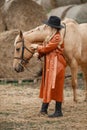 Woman in red leather coat touching a brown horse on a farm Royalty Free Stock Photo