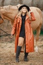 Woman in red leather coat touching a brown horse on a farm Royalty Free Stock Photo
