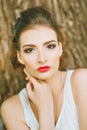 Woman with red lipstick and colored makeup, portrait in nature. Looking at the camera.