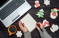 Woman with red manicure writing New year resolutions in blank notebook, copy space. Christmas background with gingerbread cookies. Royalty Free Stock Photo
