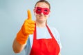 Woman in red mask, gloves and apron showing thumb up. Super housewife