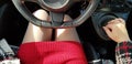 Woman in red mini dress sitting on drivers seat of italian car