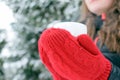 Woman with red mittens holding a mug