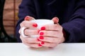 Woman with red nail polish holding white cup in a cafee Royalty Free Stock Photo