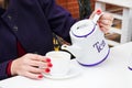 Woman with red nail polish pouring a tee in a cup in a cafee