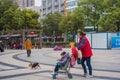 A woman in red pushed a stroller past a dog and passed by zheng he park.